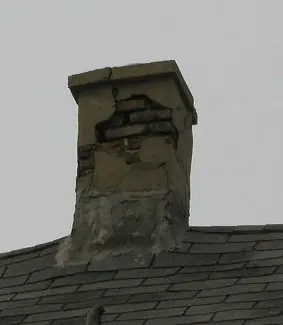 Chimney stack mid-rebuild with fresh mortar joints and a new crown