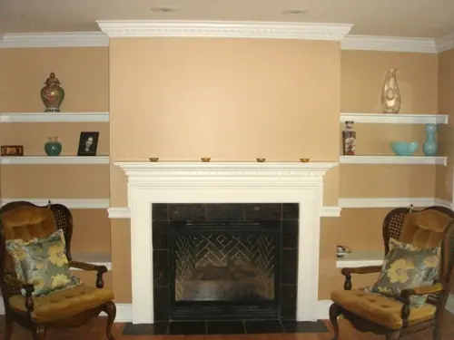 Living room fireplace with a white painted mantel, dark tile surround and two armchairs either side