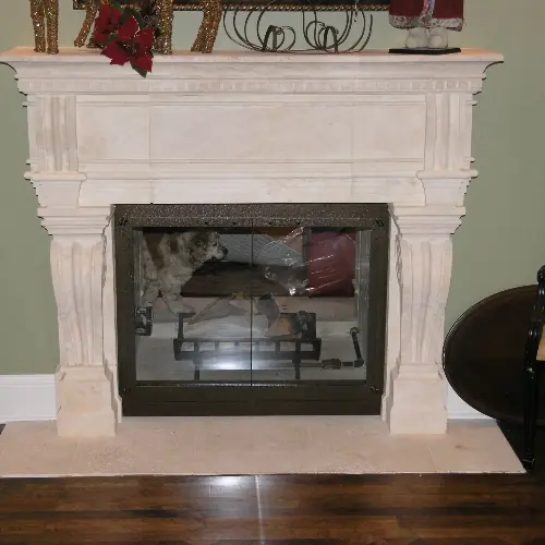 Cast stone fireplace surround fitted with bronze-framed glass fireplace doors