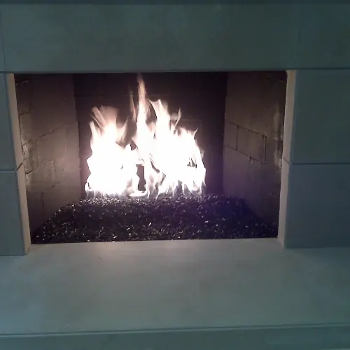 Contemporary firebox with tall flames rising from a bed of dark glass media