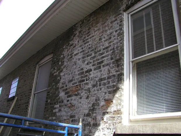 Brick wall heavily stained with white efflorescence from trapped flue moisture
