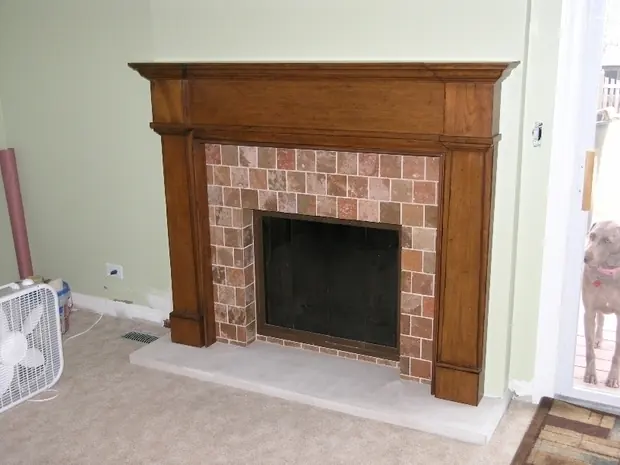 Restored fireplace with a stained timber mantel, tumbled stone surround and glass doors